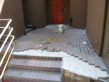 Elevated courtyard deck with brick pavers removed in an effort to identify the leak sources