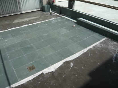 Application of slate over structural sloping mortar bed draining surface water to deck drain